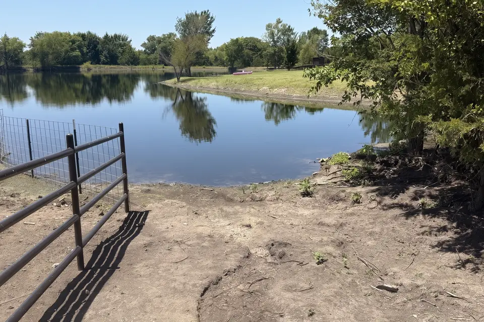 The same ranch pond after mechanical cleaning, with clean dark open water along the shoreline